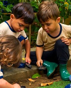 Meninos de galocha procurando bichinhos no jardim com lupas