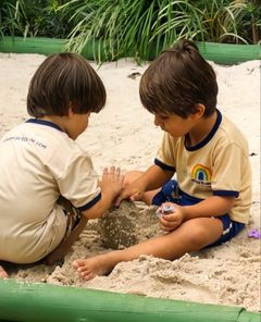 Dois meninos brincando juntos no tanque de areia
