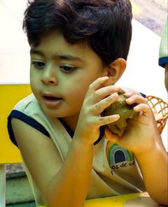 Menino modelando um pedaço de argila com as mãos