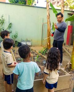 Professor explicando a horta para as crianças em volta do canteiro