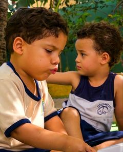 Dois meninos conversando sentados no quintal