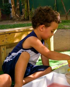 Menino brincando com água numa bacia no quintal