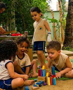 Crianças construindo uma torre de blocos de madeira no quintal