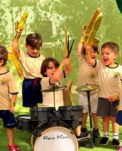 Crianças tocando bateria e erguendo aviões dourados no Rock Kids