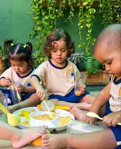 Crianças pequenas brincando com grãos e colheres no quintal