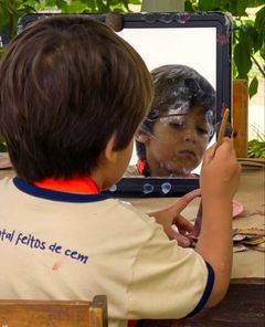 Menino pintando o próprio reflexo num espelho