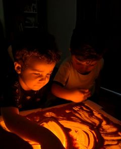 Meninos desenhando na mesa de luz com areia colorida