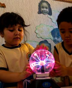 Crianças com as mãos numa bola de plasma