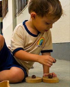 Menino encaixando bolinhas de argila em discos de madeira